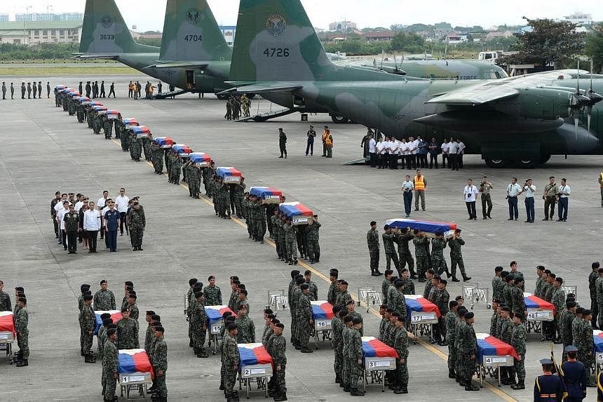 Philippine police commandos carrying the flag-draped coffins of their fallen comrades from C-130 planes shortly after arriving at a military base in Manila on Jan 29, 2015. -- PHOTO: AFP&nbsp;