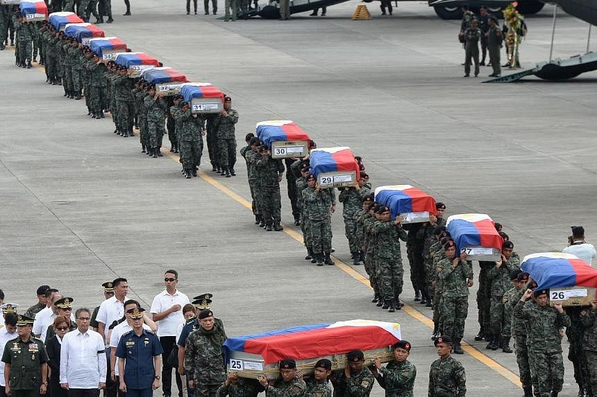 Philippine police commandos carrying the flag-draped coffins of their fallen comrades from C-130 planes shortly after arriving at a military base in Manila on Jan 29, 2015. As many as 44 commandos were killed. -- PHOTO: AFP&nbsp;