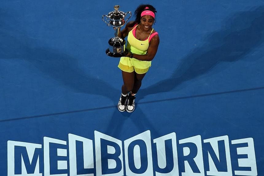 Serena Williams of the US poses with the trophy as she celebrates after victory in her women's singles final match against Russia's Maria Sharapova on day thirteen of the 2015 Australian Open tennis tournament in Melbourne on Jan 31, 2015. -- AFP