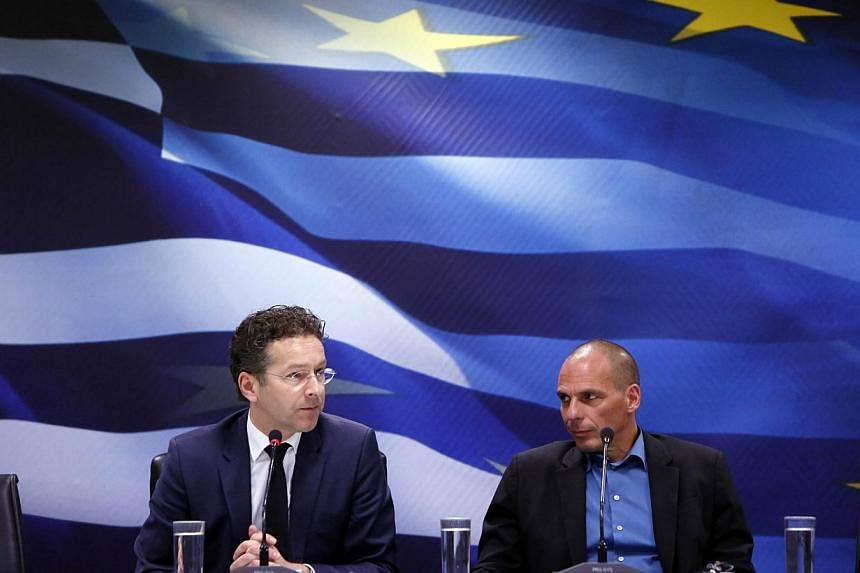 Jeroen Dijsselbloem, (left) head of the euro zone finance ministers' group, and Greek Finance Minister Yanis Varoufakis listen to a journalist's question during their common press conference at the ministry in Athens, on Jan 30, 2015. -- PHOTO: REUTE