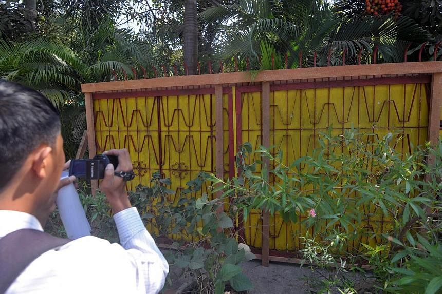 A journalist films an old gate of the Chairman of National League for Democracy (NLD) Aung San Suu Kyi's residence in Yangon on Jan 31, 2015. -- PHOTO: AFP