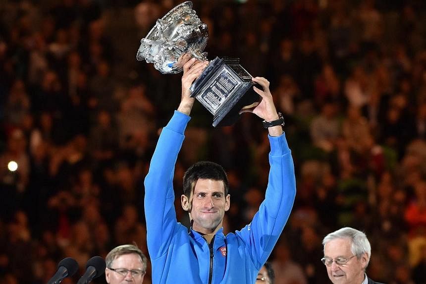 Novak Djokovic of Serbia (centre) holds up the winner's trophy at the awards ceremony as he celebrates his victory over Andy Murray of Britain in their men's singles final match on day 14 of the 2015 Australian Open tennis tournament in Melbourne on 
