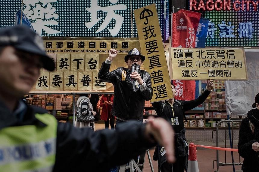 A policeman direct pedestrians as demonstrators shout slogans before a march for democracy in Hong Kong on Feb 1, 2015. -- PHOTO: AFP