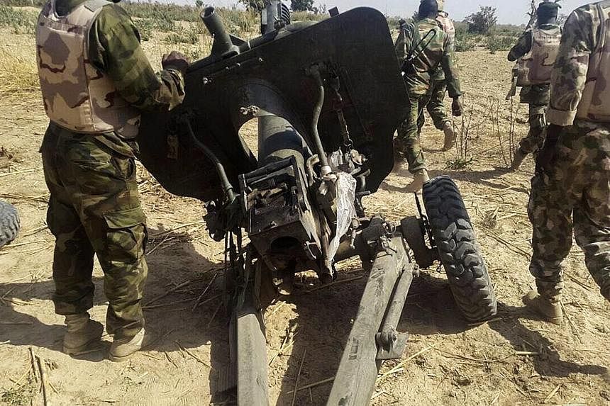 Nigerian soldiers walking near a captured field artillery piece that had been used by Boko Haram militants, in Maiduguri, in north-east Nigeria, on Jan 27, 2015. Boko Haram fighters on Sunday, Feb 1, launched a fresh attempt to take over the strategi