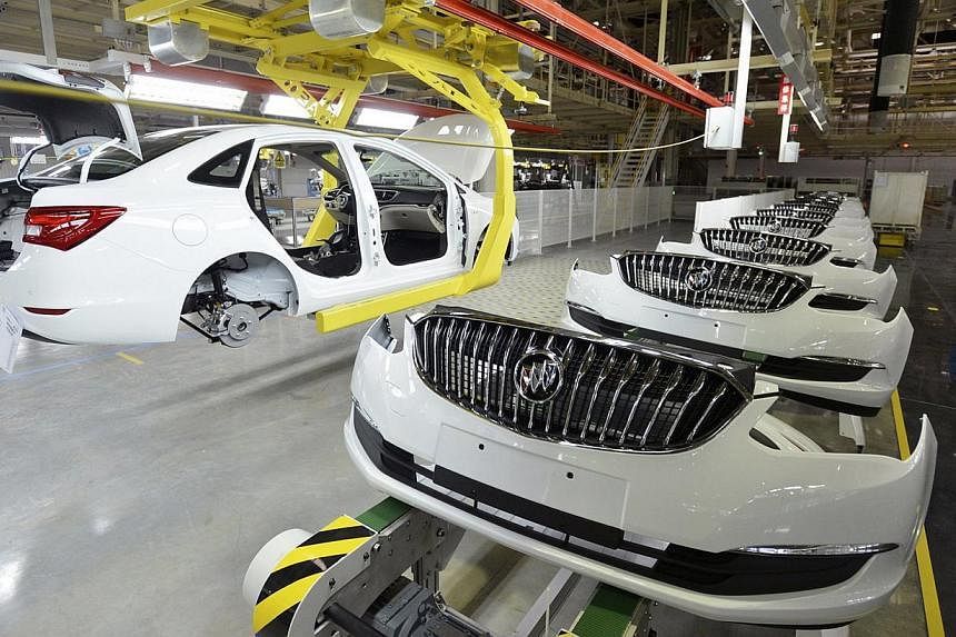 An employee looks on next to an assembly production line of Buick cars at a General Motors factory in Wuhan, China. Activity in China's factory sector contracted in January for the first time in more than two years, an official survey showed. -- PHOT