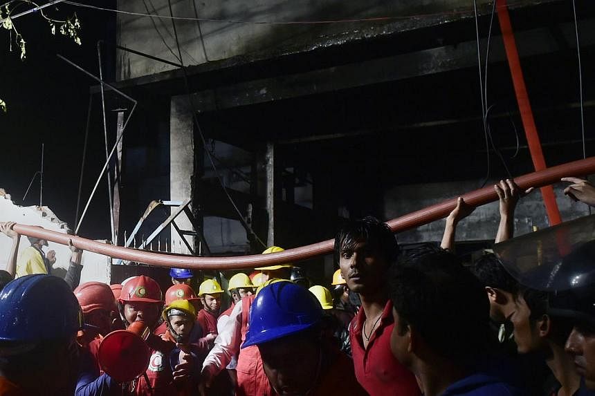 Bangladeshi volunteers and residents lift up a hosepipe as firefighters try to extinguish a fire in a plastic factory in Dhaka on Jan 31, 2015.&nbsp;Bangladesh on Sunday ordered an enquiry into a plastics factory fire that killed 13 workers, the late