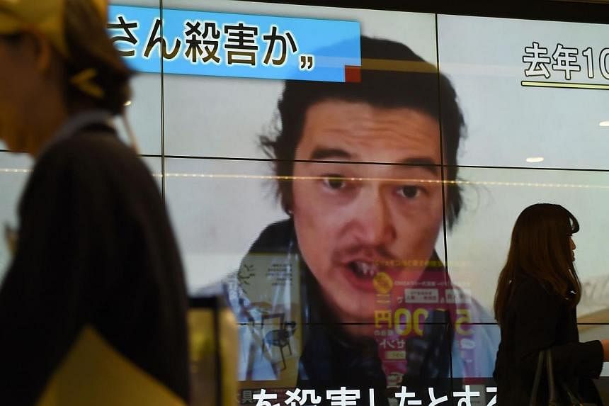 People walk past a big screen reporting that Japanese hostage Kenji Goto was killed by the Islamic State in Tokyo on Feb 1, 2015. -- PHOTO: AFP&nbsp;