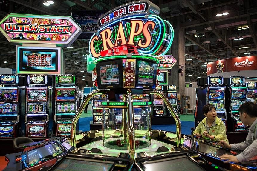 In this file picture taken on May 20, 2014, visitors try a machine at the Global Gaming Expo Asia in the world’s biggest gambling hub of Macau. -- PHOTO: AFP