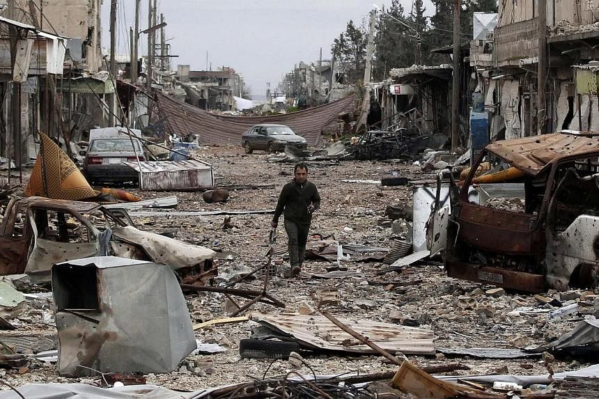 A man walks down a street filled with abandoned vehicles and debris from damaged buildings in the northern Syrian town of Kobane on Jan 30, 2015.&nbsp;Islamic State in Iraq and Syria (ISIS) militants are withdrawing from areas around Kobane, a group 
