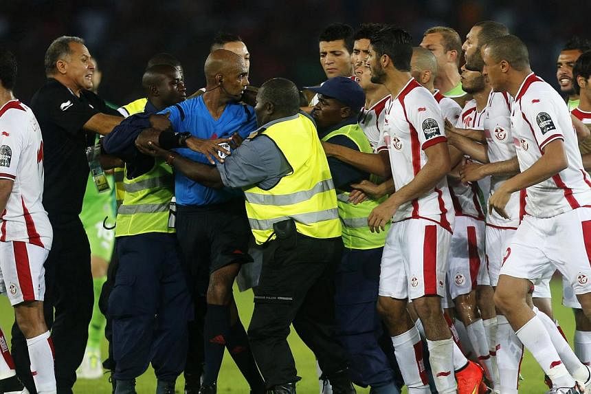 Tunisia players confront referee Seechurn Rajindraparsad (in blue) after losing their quarter-final football match of the 2015 African Cup of Nations against Equatorial Guinea in Bata on&nbsp;Jan 31, 2015. Tunisia are facing heavy punishment after th