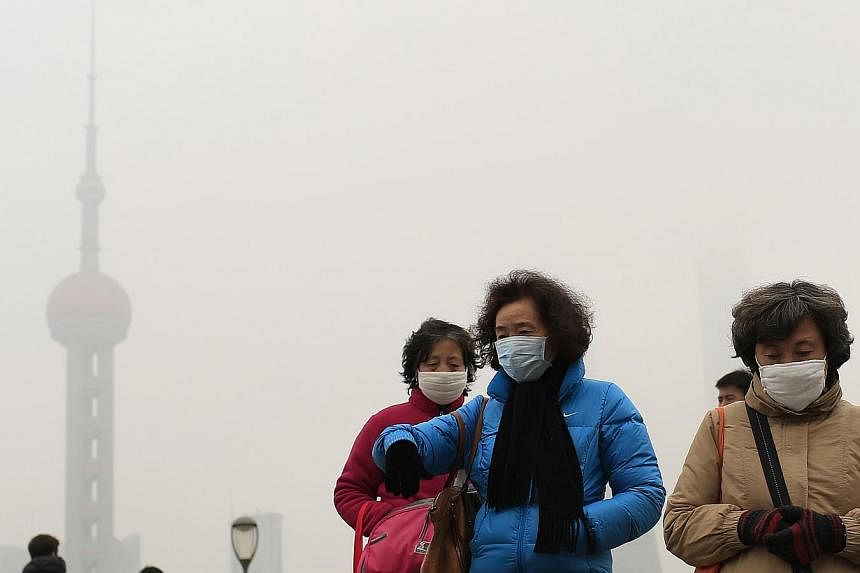 Woman wearing face masks on the Bund in front of the Oriental Pearl TV Tower during a hazy day in downtown Shanghai on Jan 26, 2015. -- PHOTO: REUTERS