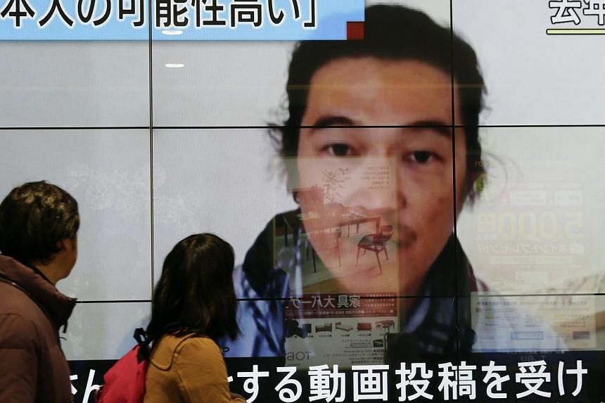Passersby watching an image of Kenji Goto pictured on last October with news reporting the Japanese hostage was killed by an Islamic State militant. The United Nations Security Council demanded the immediate release of all hostages held by the Islami