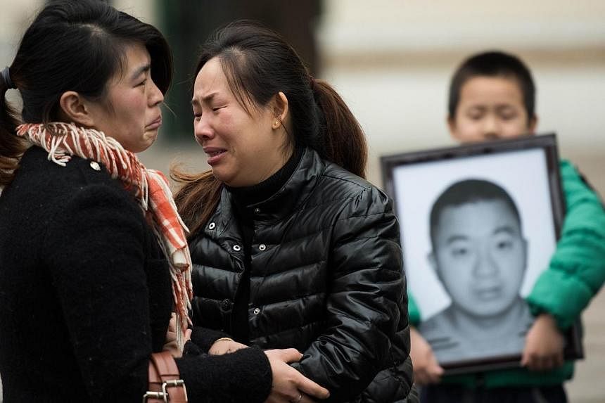 Ms Fan Ping (centre), wife of Du Shuanghua, who died in a stampede on New Year's Eve, cries after the funeral ceremony of her husband, next to her son who is holding a portrait, in Shanghai on Feb 3, 2015.&nbsp;Du's funeral was held on Tuesday, after