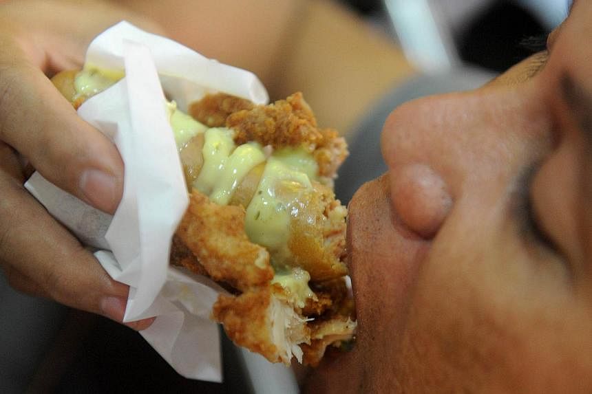 A man eats a "Double Down Dog," in Manila on Feb 3, 2015, a product conceived and introduced by the Philippine franchise of KFC.&nbsp;The dish, a hotdog wrapped in fried chicken instead of bread and covered in cheese sauce, has horrified dieticians, 