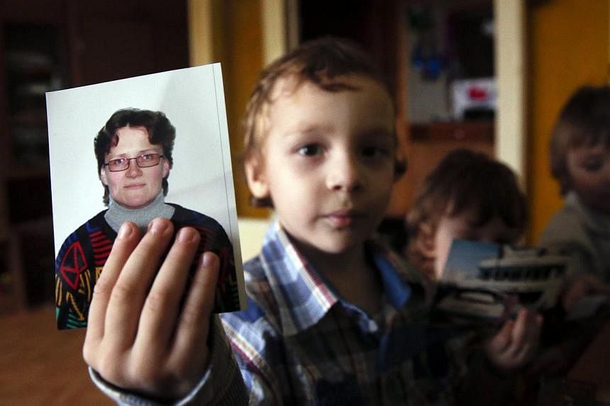 Artur, son of Russian activist Svetlana Davydova and her husband Anatoly Gorlov, holds up a photo of his mother to the camera, at their home in Vyazma, nine months after she was arrested on suspicion of treason. -- PHOTO: REUTERS