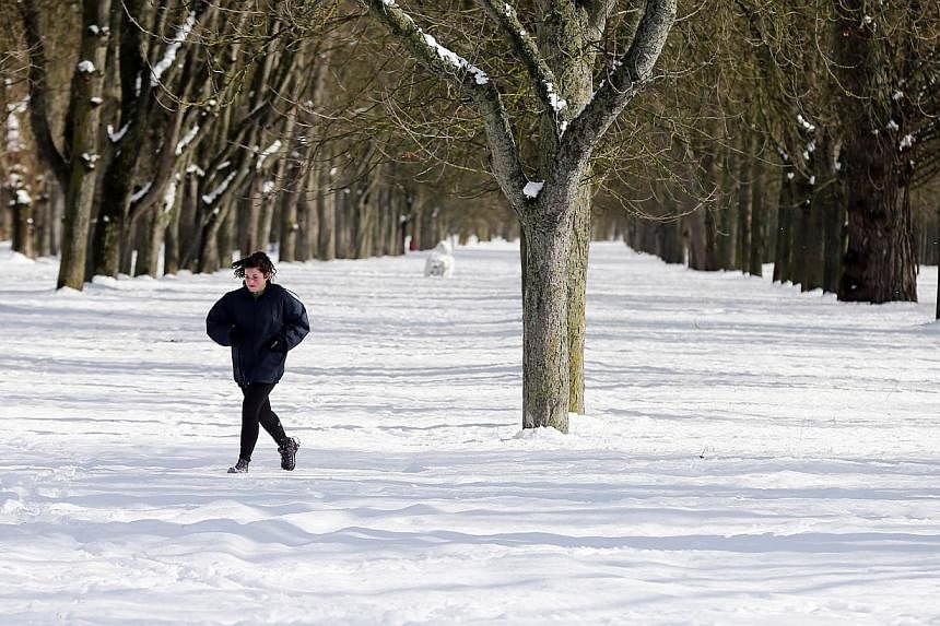 A woman jogs across snow covered la Quinta Park after a heavy snowfall in Burgos, Spain on Sunday. -- PHOTO: AFP&nbsp;