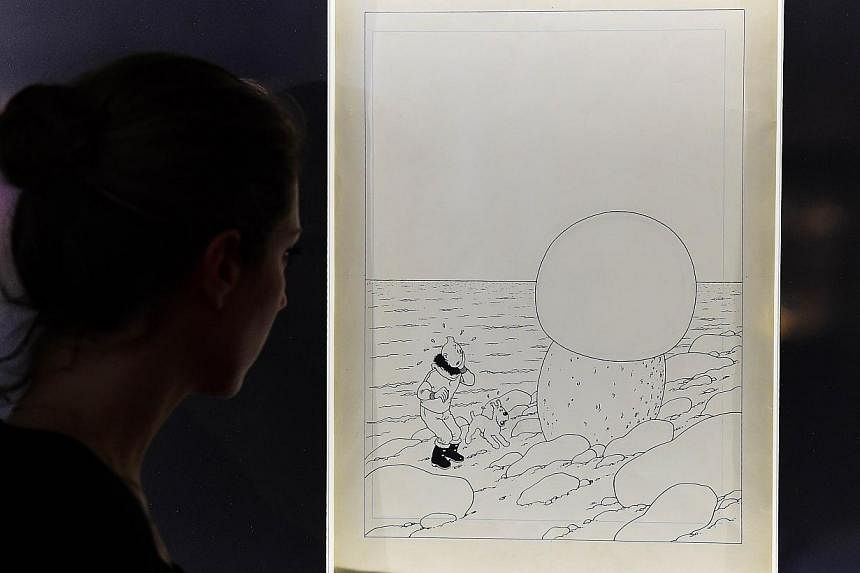A woman looks at the original artwork to the cover of Tintin et L'etoile Mysterieuse (Tintin And The Shooting Star) by late Belgian cartoonist Herge at the Brussels Antiques and Fine Art Fair, in Brussels. -- PHOTO: AFP