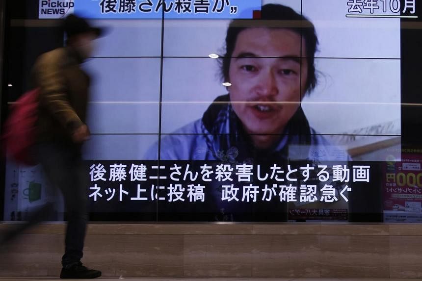 A pedestrian walks past television screens displaying a news program about Japanese journalist Kenji Goto, who was held hostage by Islamic State militants, on a street in Tokyo on Feb 1, 2015.&nbsp;The Islamic State in Iraq and Syria (ISIS) has commi