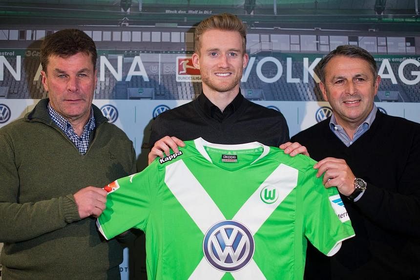 New Signing Andre Schuerrle poses as he is presented to play for German Bundesliga soccer team VfL Wolfsburg standing next to trainer Dieter Hecking (left) and team manager Klaus Allofs at the Volkswagen-Arena in Wolfsburg, Germany, on Feb 04, 2015.&