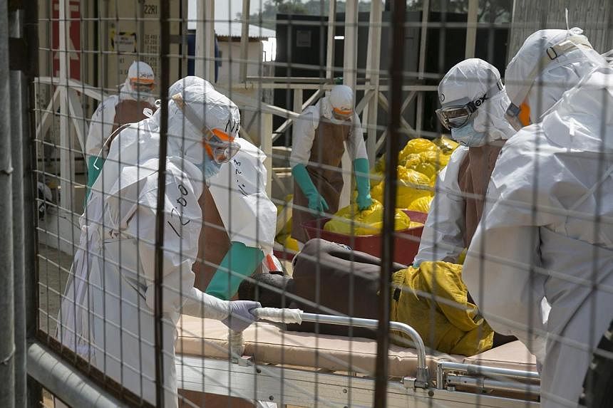 British health workers lifting a newly admitted Ebola patient onto a wheeled stretcher in to the Kerry town Ebola treatment centre outside Freetown, Sierra Leone, on Dec 22, 2014. -- PHOTO: REUTERS &nbsp;