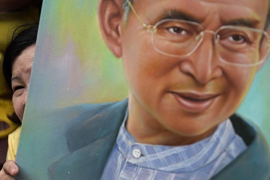 Thai well-wishers hold portraits of King Bhumibol Adulyadej as they gather at Siriraj Hospital where the king has spent most of the last few months, on the occasion of his 87th birthday in Bangkok on Dec 5, 2014.&nbsp;Thai police on Wednesday said th