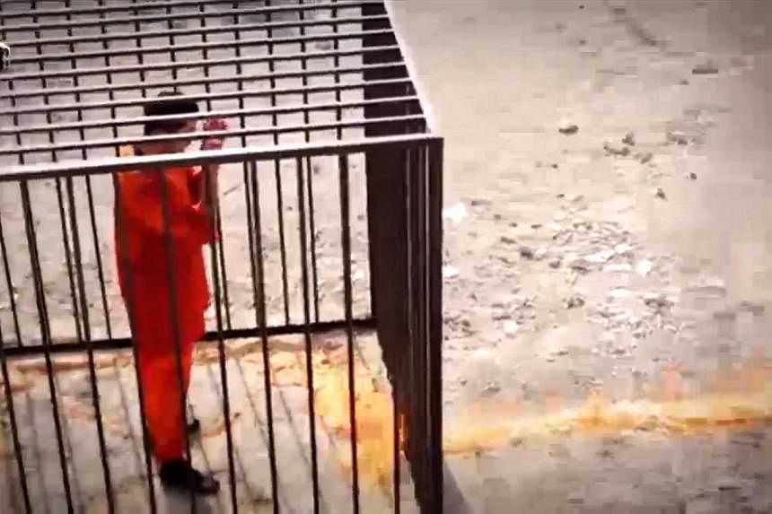 Jordanian pilot Muath al-Kasaesbeh is seen standing in a cage as the flame begins to engulf the metal cage. -- SCREENGRAB / YOUTUBE