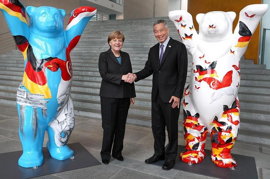 German Federal Chancellor Angela Merkel and Prime Minister Lee Hsien Loong shake hands at the Federal Chancellery in Berlin on Feb 3 2015. They are flanked by the two winning entries of the Buddy Bear Design competition organised by the Singapore Emb