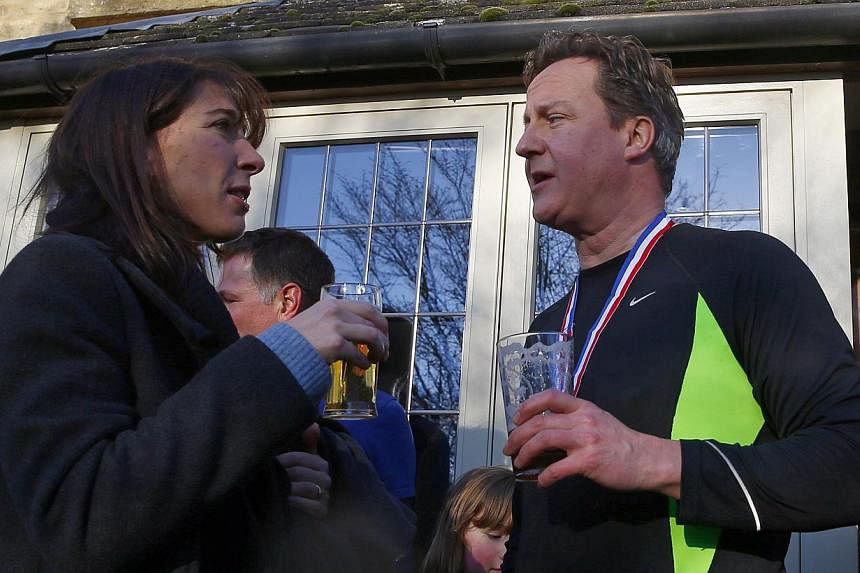British Prime Minister David Cameron enjoys a beer with his wife Samantha (left) after competing in the Great Brook Run, a mile-long course through water and mud, at Chadlington in southern England Dec 29, 2014. -- PHOTO: REUTERS