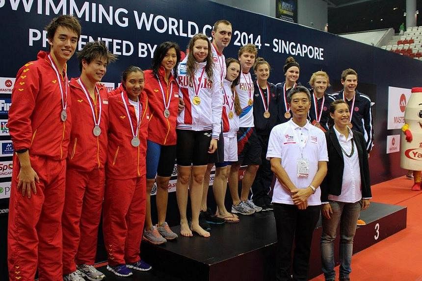 Singapore swimmers (in red, from left) Lukas Menkhoff, Russell Ong, Nur Marina Chan and Amanda Lim posing with the teams from Russia and the US and (in front) Yakult Singapore director Shinichi Uekusa and Singapore Swimming Association (SSA) vice-pre