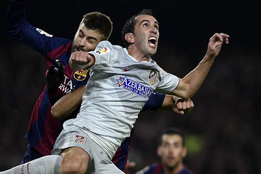 Atletico Madrid defender Diego Godin (right) vies with Barcelona's&nbsp;Gerard Pique&nbsp;during their Spanish league football match at the Camp Nou stadium in Barcelona on Jan 11, 2015. Godin has hit out at the media's labelling of his team's playin