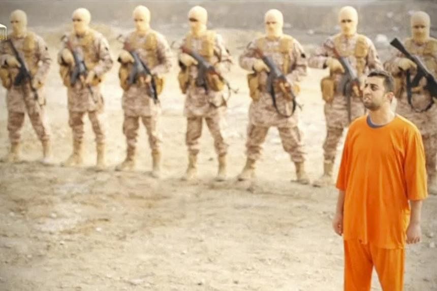 Islamic State captive, Jordanian pilot Muath al-Kasaesbeh, stands in front of a row of armed militia in this photo still of a video released on social media. He was later seen being gruesomely burnt alive in a black cage. -- PHOTO: REUTERS