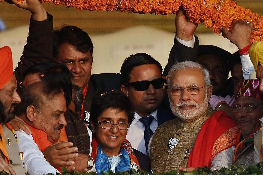 Supporters of India's ruling Bharatiya Janata Party (BJP) present a garland to Prime Minister Narendra Modi (front third right) during a campaign rally ahead of state assembly elections in New Delhi on Jan 31, 2015. He faces the first real test of hi