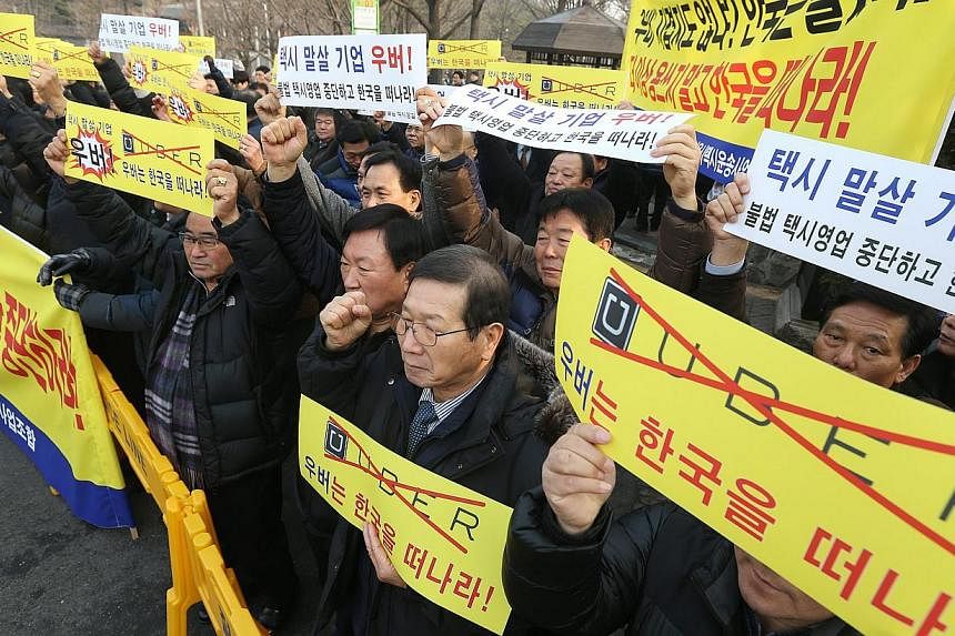 South Korean taxi drivers and taxi industry officials hold a rally in downtown Seoul, South Korea, on Feb 4, 2015, demanding that web-based taxi company Uber withdraw from the South Korean market. -- PHOTO: EPA