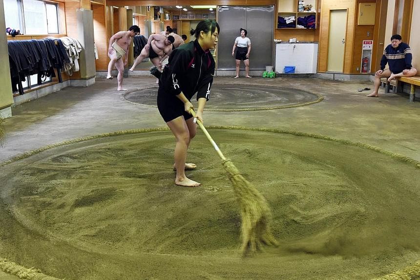 Female sumo wrestler Shiori Kanehira cleaning the ring during a training session at Nihon University's sumo club in Tokyo. -- PHOTO: AFP