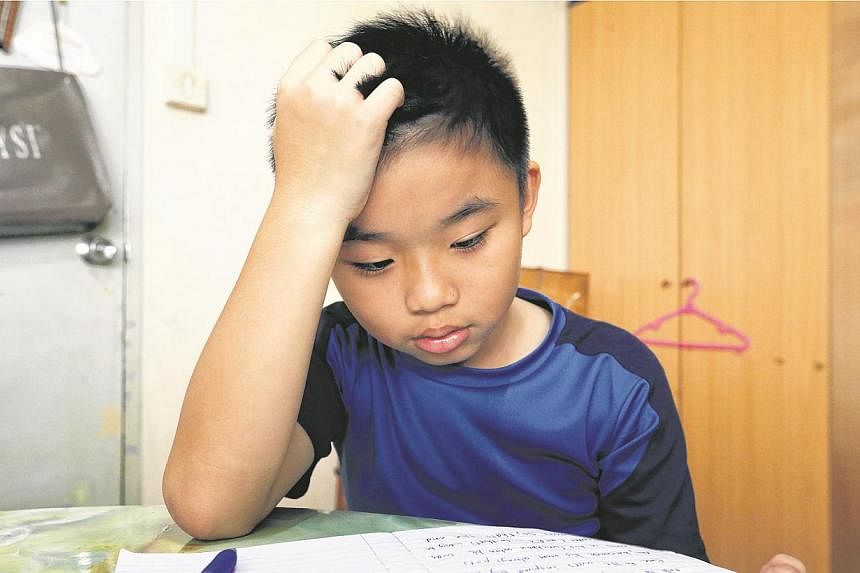 Tay Danzel, 10 trying to concentrate on his homework. More than a third of lower primary school pupils are not getting enough sleep, but only 8 per cent of parents recognise that their child may have sleep problems. -- ST PHOTO: CHEW SENG KIM
