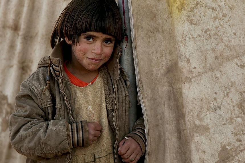 A displaced Iraqi child from the minority Yazidi sect stands outside her tent at a refugee camp on Nov 29, 2014. -- PHOTO: REUTERS