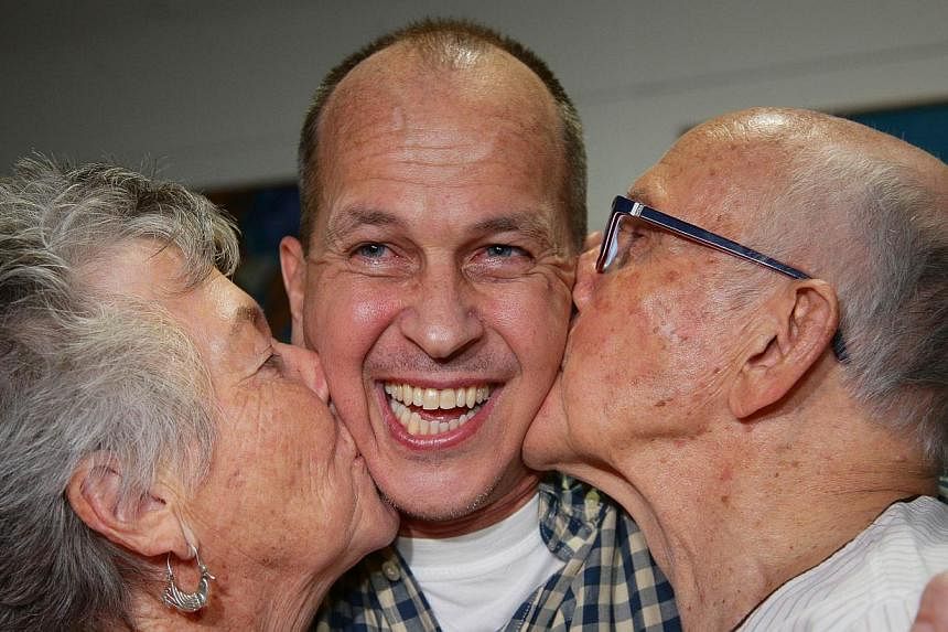 Al-Jazeera journalist Peter Greste is kissed by his mother Lois (left) and father Juris upon his arrival at Brisbane's international airport in the early hours of Feb 5, 2015. -- PHOTO: AFP