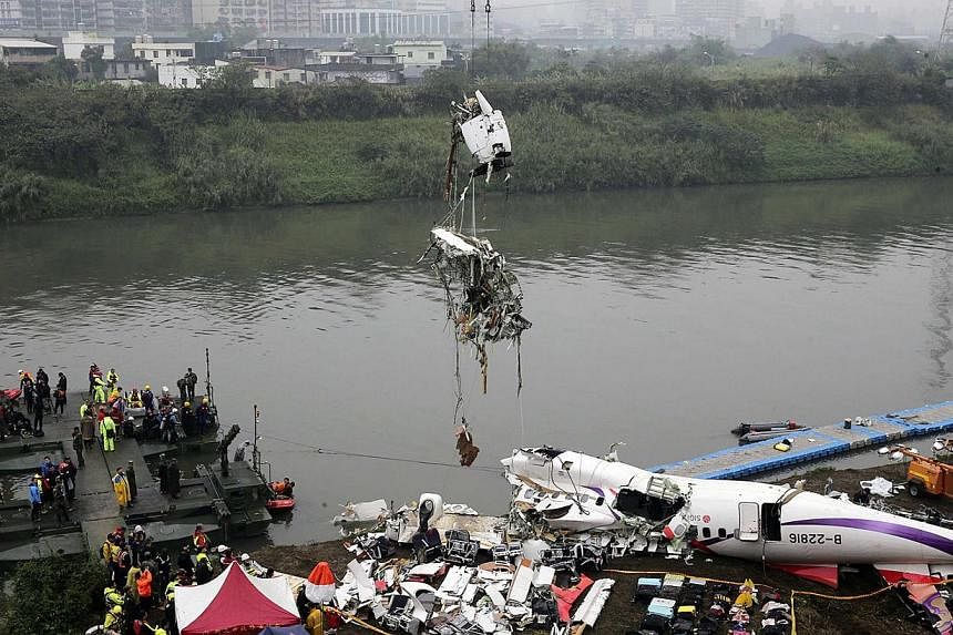 Rescuers lift part of the wreckage of TransAsia Airways plane Flight GE235 after it crash landed into a river, in New Taipei City, on Feb 5, 2015. Taiwanese rescue officials refused to give up hope of finding 12 people still missing, more than 24 hou
