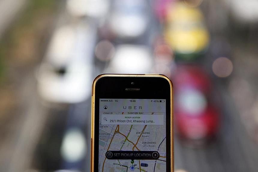 A phone running the Uber application being held above traffic in central Bangkok.&nbsp;Uber has grown into one of the world's largest startups, valued at some US$40 billion (S$53.9 billion), with operations in more than 200 cities in 54 countries aro