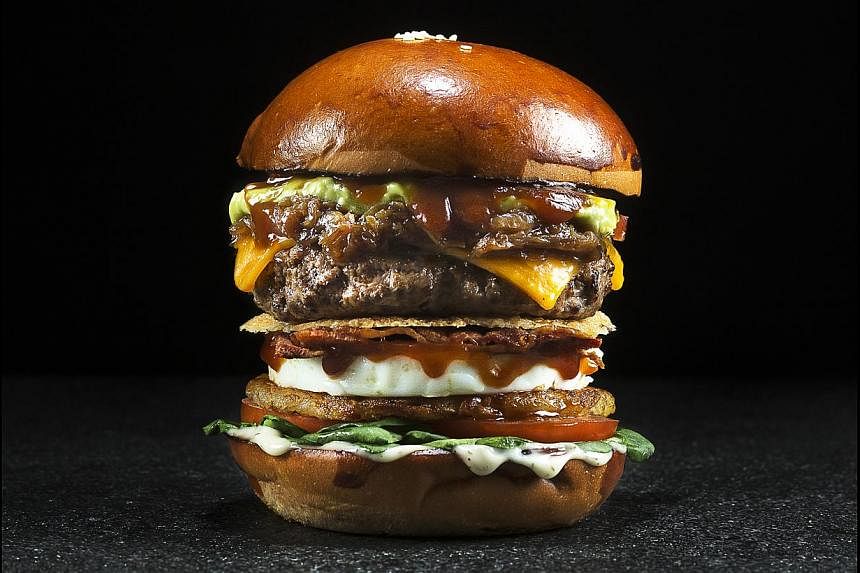 The Works is a substantial burger with baby spinach, bacon weave, rosti potatoes, parmesan crisp, onion ring, fried egg, sliced tomatoes, beer-caramelised onions and&nbsp;guacamole. -- PHOTO: WILDFIRE KITCHEN + BAR