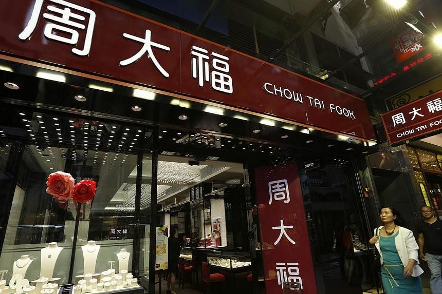 People walk in front of a Chow Tai Fook jewellery store in Hong Kong in this June 17, 2014. Hong Kong-based Chow Tai Fook group, owner of the world's biggest jewellery company, is making an unlikely foray into China's oil trading business, according 