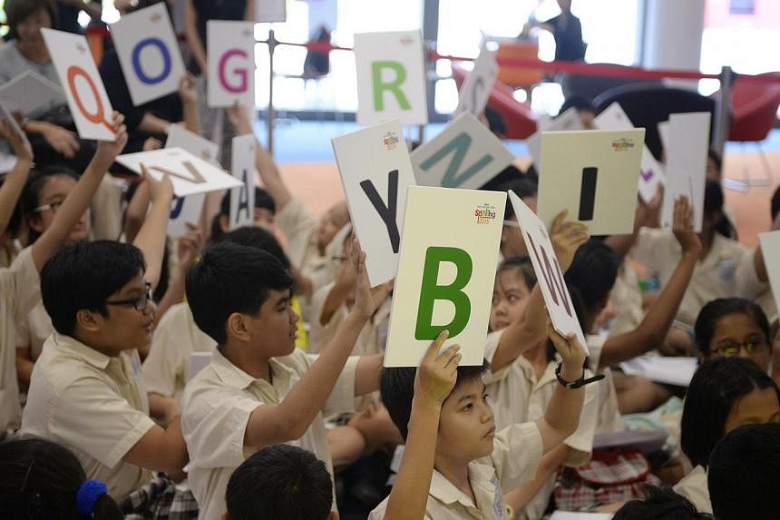 Yishun Primary 5 students hold up cards with letters during a friendly spell-off against Singapore Chinese Girls' School at the launch of the fourth edition of the annual RHB-The Straits Times National Spelling Championship held at Singapore Sports H