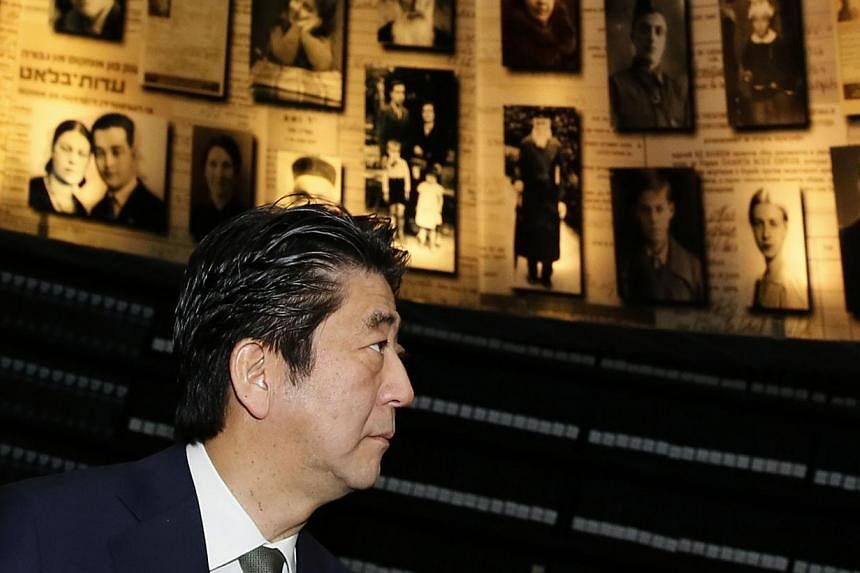 Japanese Prime Minister Shinzo Abe and his wife Akie look at pictures of Jewish Holocaust victims at the Hall of Names on Jan 19, 2015 during their visit to the Yad Vashem Holocaust Memorial museum in Jerusalem commemorating the six million Jews kill