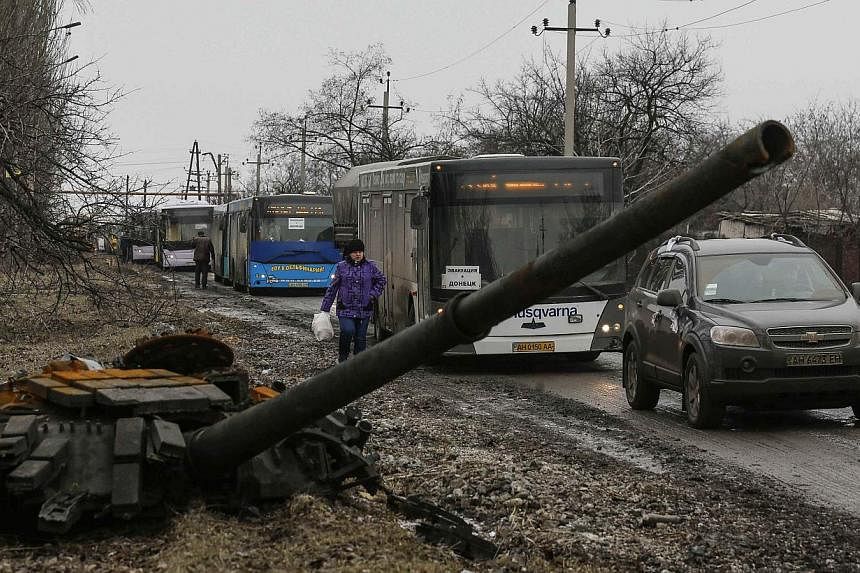 Empty buses, intended for internally displaced persons (IDPs), wait along a road beside a burnt-out tank turret while travelling in the direction of the village of Debaltseve to evacuate the residents, in Vuhlehirsk, Donetsk region on Feb 6, 2015.&nb