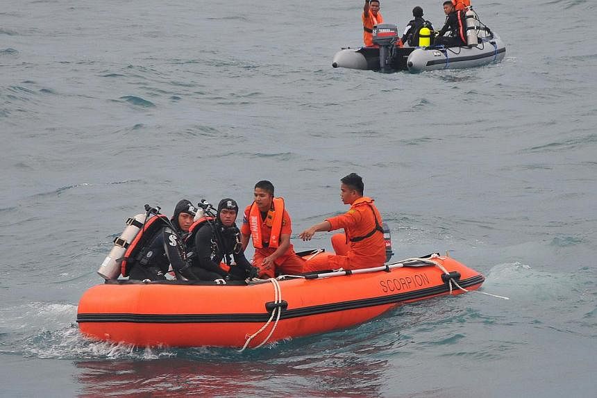 In this Feb 2, 2015 photo, Indonesian divers and rescue personnel from the National Search and Rescue Agency recover a body from the underwater wreckage of the ill-fated AirAsia flight QZ8501 in the Java sea. -- PHOTO: AFP
