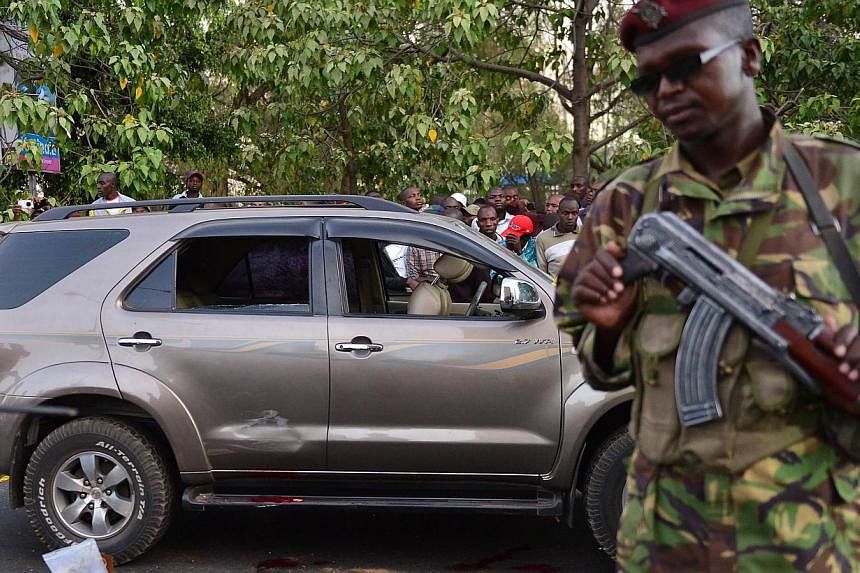 A police officer stands near the blood stained vehicle of prominent government MP Hon George Muchai after he was shot dead by gunmen early morning in Nairobi, on Feb 7, 2015, along with his two bodyguards and driver according to a senior police offic