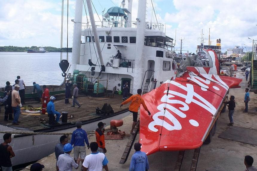 Workers load the tail of AirAsia flight QZ8501 onto a truck at Kumai sea port, in Central Kalimantan on Feb 7, 2015, before they transport it to Jakarta. Indonesian divers have found a body believed to be French co-pilot Remi Plesel, who was steering