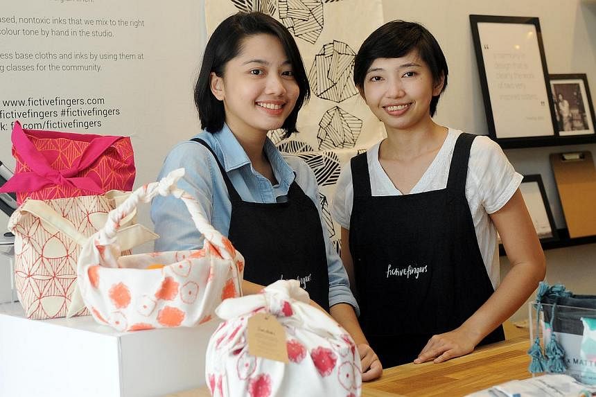 Fictive Fingers' Hani and Aisah Dalduri (both above) have designed a special Japanese wrap cloth that can be used to hold food. Wet Tee Shirt's (from far left) sales manager Benson Khee, owner Brandon Lee and customer service officer Edmund Chew in t