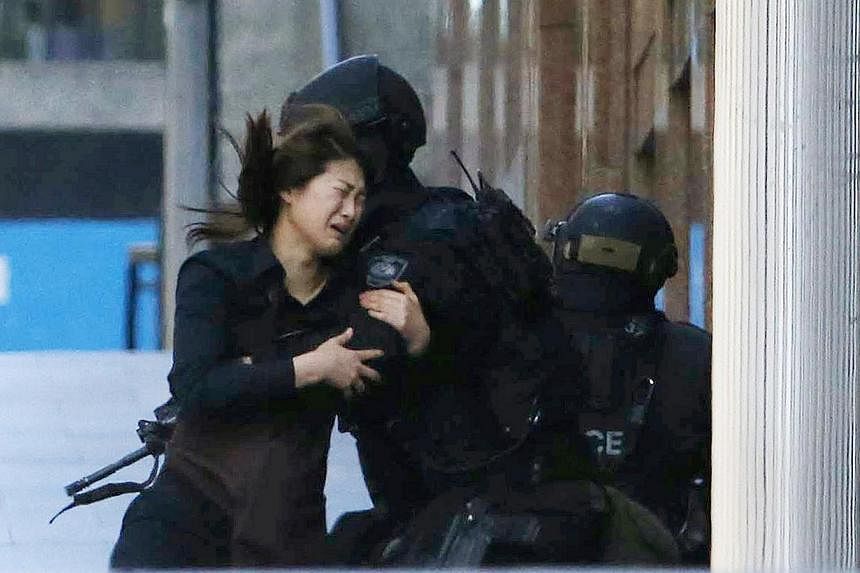 A hostage running towards a police officer outside the Lindt cafe, where other hostages were being held, in Martin Place in central Sydney on Dec 15, 2014.&nbsp;Survivors of the 16-hour siege on Sunday, Feb 8, 2015, told of their terror during the de