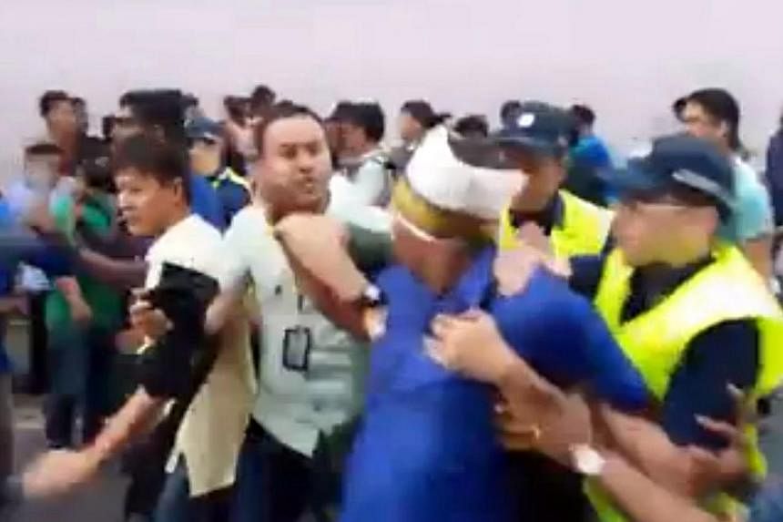A screenshot of a video posted on Facebook showing a man being led away by police during a scuffle at the Thaipusam procession on Feb 3, 2015 .&nbsp;A 30-year-old Indian woman has filed a police report claiming that she was pushed and hit by cops dur